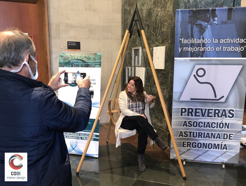 D. Gonzalo Huerta de PREVERAS realizando una fotografía a Miryam Hernández, Directora del Instituto Asturiano de Prevención de Riesgos Laborales (IAPRL), en la silla columpio Swing.